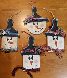 three snowman ornaments hanging on a wooden table