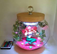 a fish bowl with a little mermaid in it and a remote control on the side