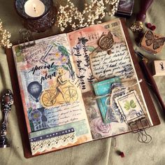 an open book with various items on it and some flowers next to it, including a candle