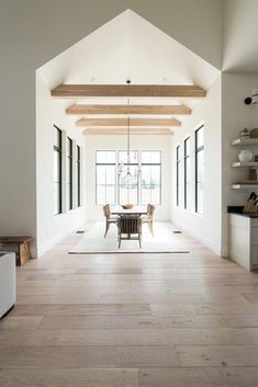 an open floor plan with white walls and wood beams in the dining room, along with large windows