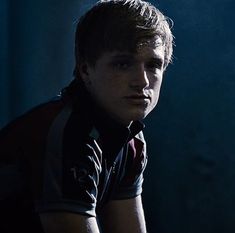 a young man sitting down in the dark