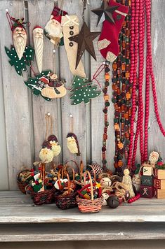 an assortment of christmas decorations hanging on a wooden wall next to a shelf with other items