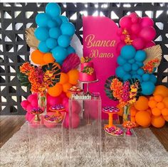 an assortment of colorful balloons and desserts on display in front of a pink backdrop