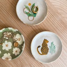 three plates with animal designs on them sitting on a wooden table next to scissors and thread