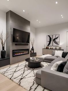 a living room with a large gray couch and fireplace in the corner, surrounded by white rugs