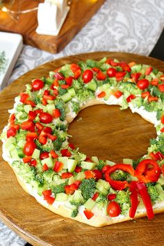 a pizza covered in veggies on top of a wooden platter