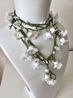 a white mannequin with flowers and pearls on it's neckpieces