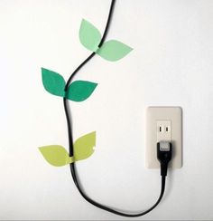 an electrical outlet plugged into a wall with a plant on it's side