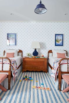 two twin beds in a room with blue and white wallpaper, striped rugs