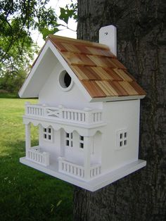 a white bird house on the side of a tree