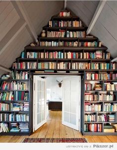 a room filled with lots of books on top of a book shelf next to a doorway