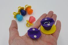 a hand is holding some colorful dices in it's palm and several other small ones are on the table