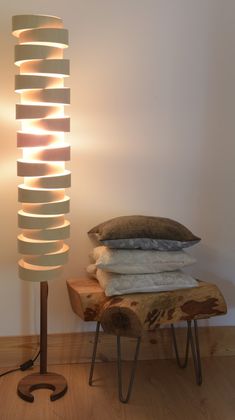 a lamp that is sitting next to a pile of blankets on a stool with a pillow