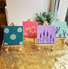 three small easels with painted flowers on them