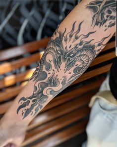 a man's arm with a dragon tattoo on it and flames in the background