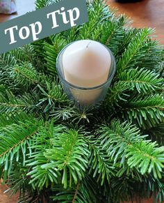 a candle sitting on top of a table next to pine cones and greenery with the words top tip written above it