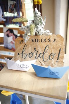 a sign that says be - vindos a bordio with paper boats on it