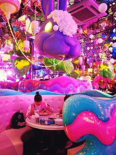 a person sitting at a table in a room with balloons all over the walls and ceiling