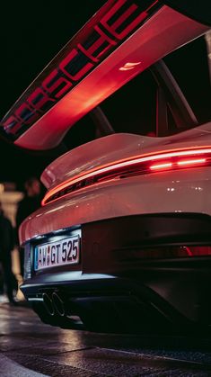 the back end of a white porsche car with red lights on it's taillights