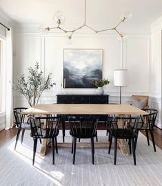 the dining room table is surrounded by black chairs and an area rug that matches the white walls