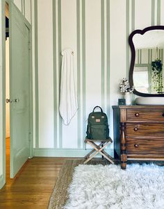 a room with a dresser, mirror and rug on the floor in front of it