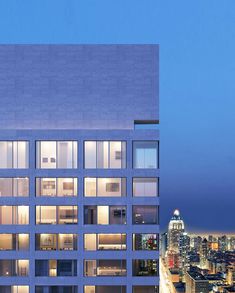 a tall building with lots of windows next to a cityscape at night time