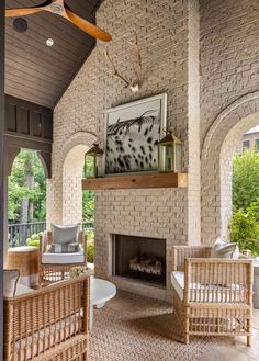 an outdoor living area with wicker furniture and fireplace in the center, surrounded by arched windows