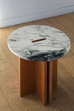 a white marble table with wooden legs on the floor