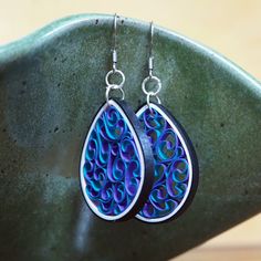 pair of earrings with blue and purple swirls on them sitting on a green plate