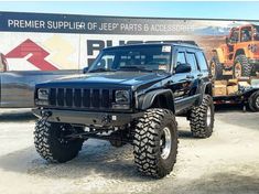 a black jeep is parked in front of a truck