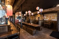 a restaurant with wooden tables and lanterns hanging from the ceiling