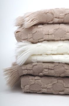 four blankets stacked on top of each other with white and beige colors in the middle