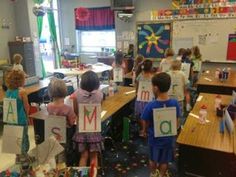 children holding up signs with the letters m and o on them in a class room