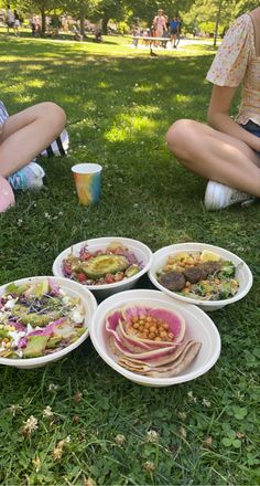 people sitting in the grass with plates of food