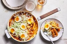 two plates with food on them next to cups and spoons, one has an egg in it