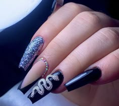 a woman's hand with black and silver nail polishes on her nails, decorated with swarovs