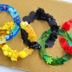 the olympic rings are made out of paper flowers and plastic straws, which have been placed on top of cardboard