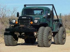 a large green truck driving down a dirt road