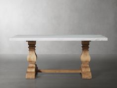 a white marble table with wooden legs on a gray floor in front of a grey wall