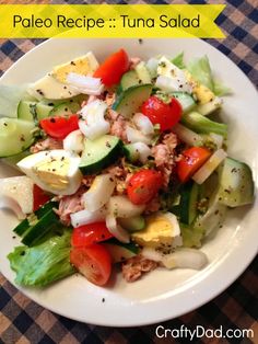 a salad with cucumbers, tomatoes, and other vegetables on a white plate