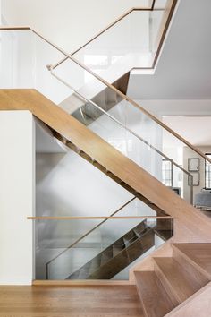 a wooden stair case with glass balustrades and wood handrails in a modern home