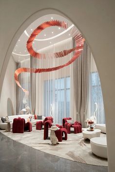 a living room filled with red couches and white chairs next to a tall window