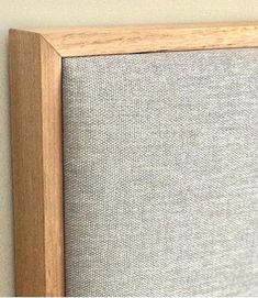 a close up view of a wooden frame on a wall with a gray fabric behind it