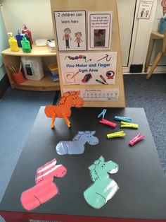 a table with some cut out animals and pencils on it in front of a bookcase