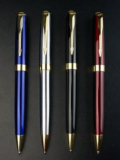 three different types of pens lined up on a black surface with gold trimmings