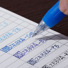 a person is writing on a piece of paper with a blue pen in their hand