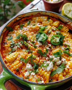 a green pot filled with corn on the cob and garnished with cilantro