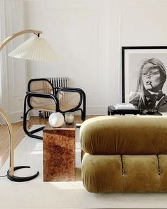 a living room filled with furniture next to a lamp and pictures on the wall behind it