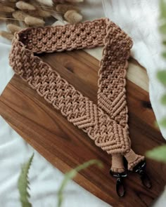 a crocheted scarf is laying on a wooden board