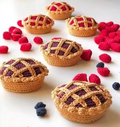 crocheted raspberry pies and blueberries are arranged on a table